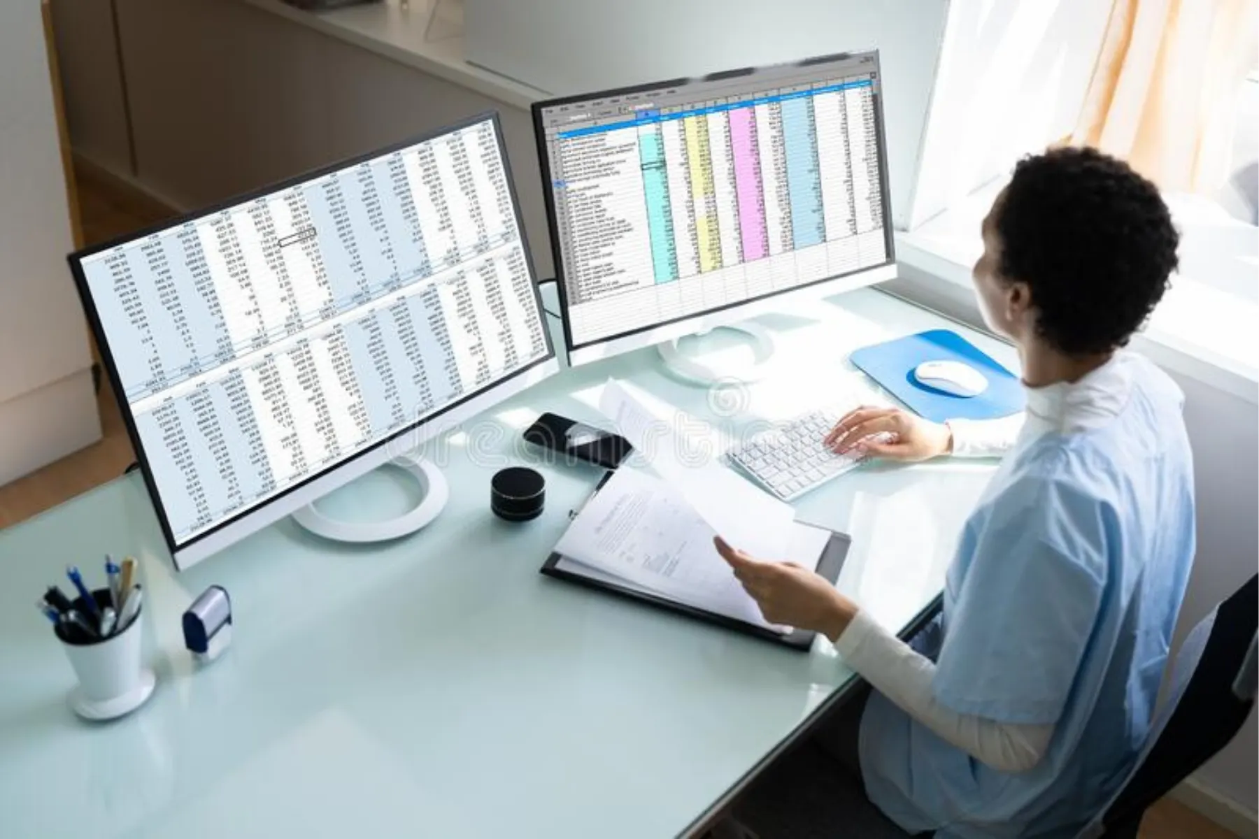 A woman at a desk, engaged in her work, with two computer monitors set up for enhanced productivity.